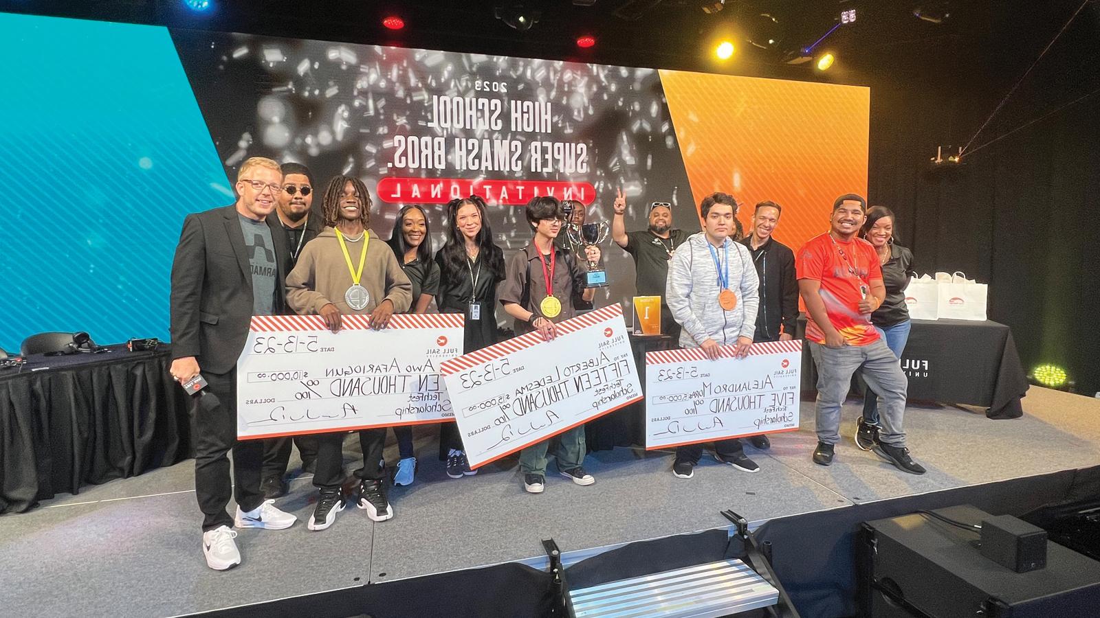 Techfest 比赛 winners holding large scholarship checks on stage alongside 满帆 staff members in the Fortress.